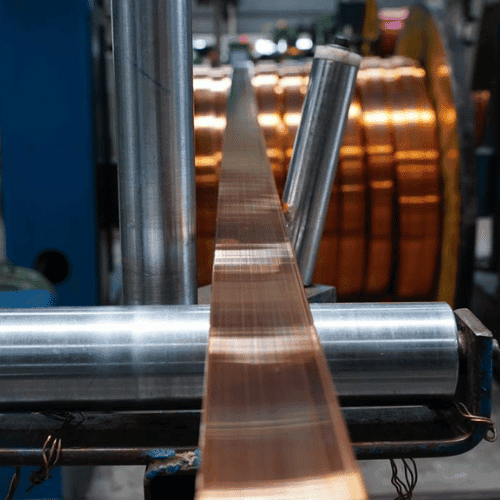 Copper busbar moving through production rollers